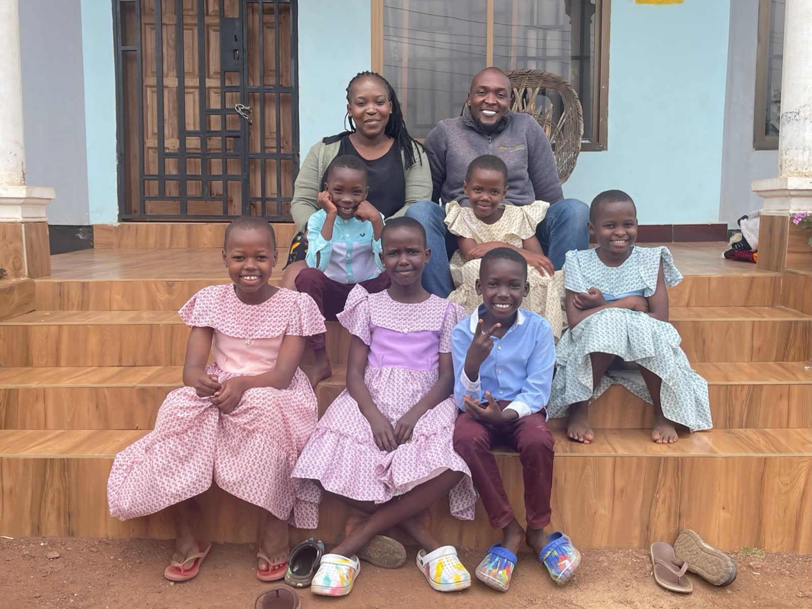 Naomi and Faraja sitting on the front steps of the house in Arusha with the children they care for.