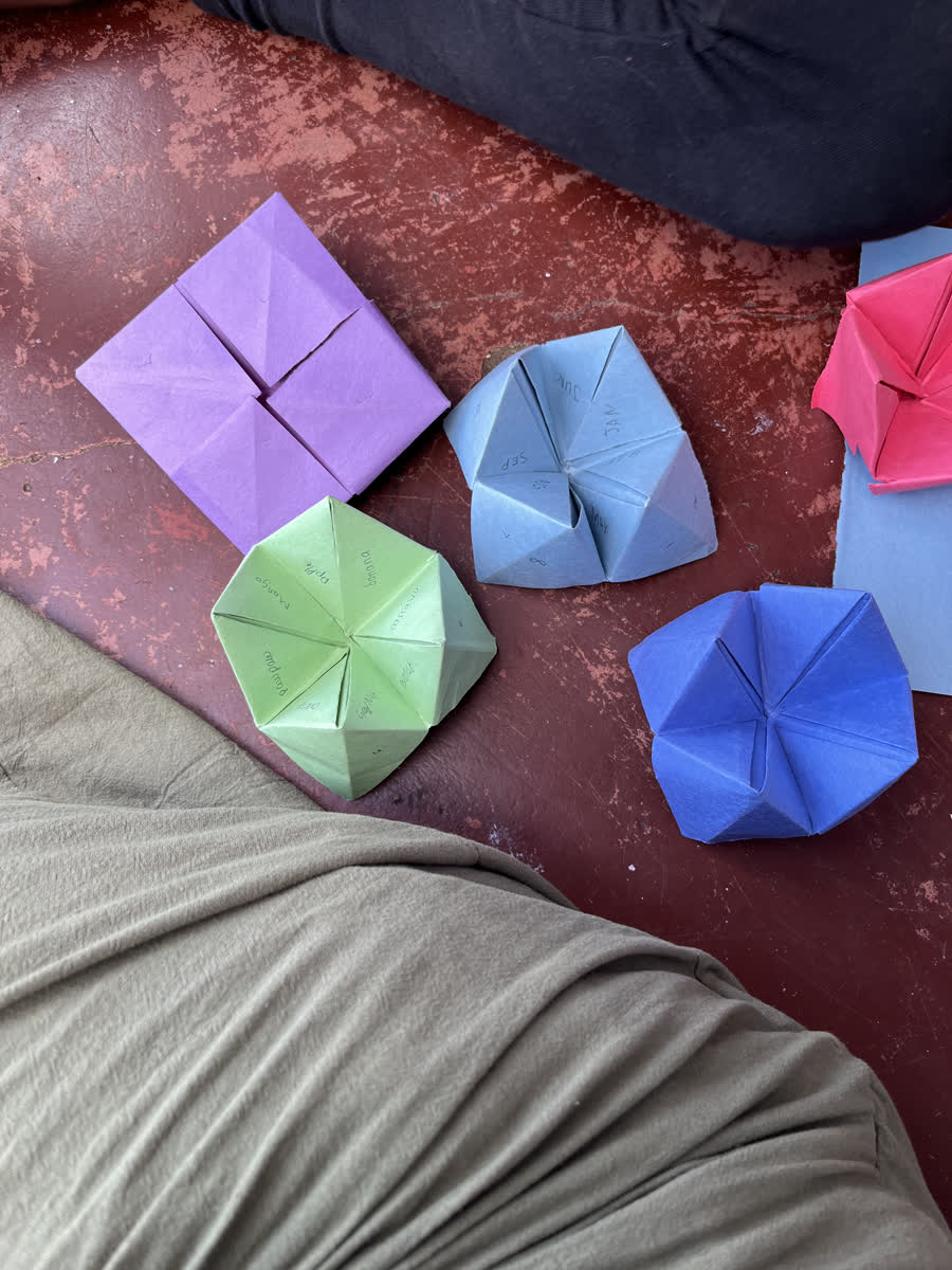 Folded paper shapes in green, blue, purple and pink laid out on a bed.
