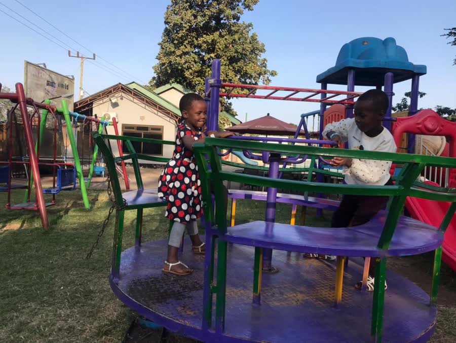 Two children turning a painted roundabout in a playground.