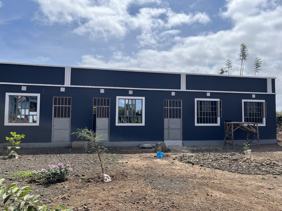 The blue school building the children attend, under a wide sky.