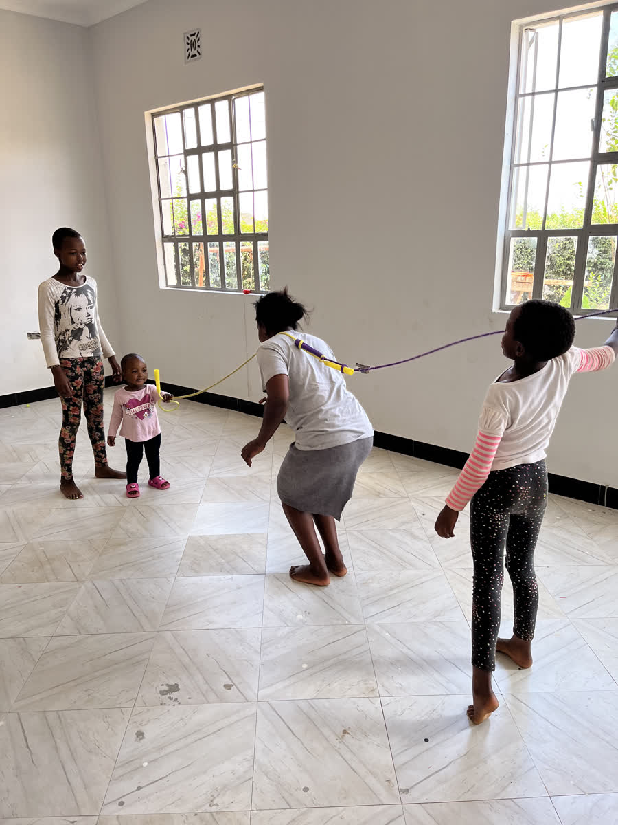 Children skipping with a rope in a bright empty room.